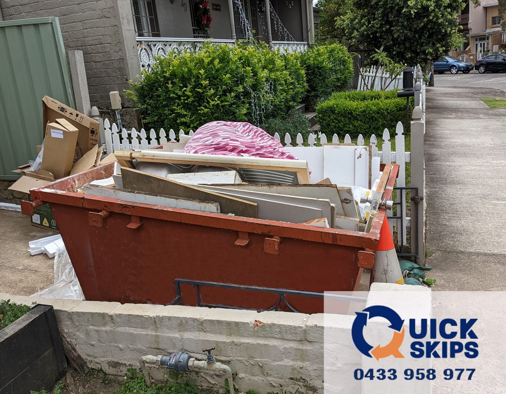 small 2 cubic meter skip bin with no door on rear side placed in driveway Inner West Sydney, while the builder is clearing out the debris from the house
