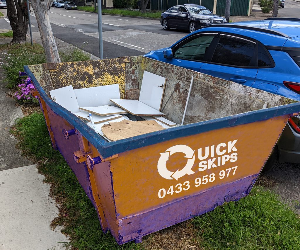 Three cubic metre skip bin hire with rear door filled with rubbish placed on the verge Fairfield area