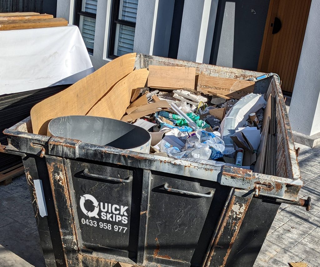 Four 4 cubic metre skip bin coloured black with wheelbarrow in the Penrith area