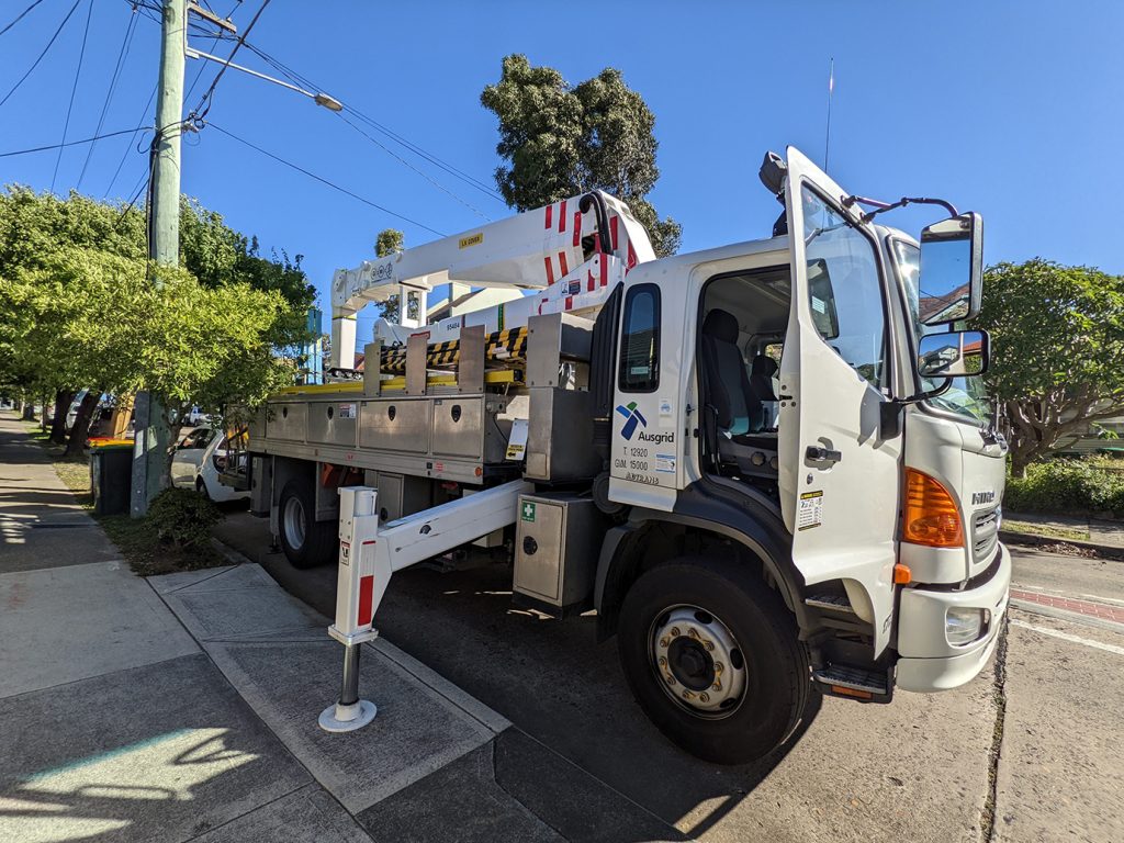 Ausgrid truck with the cherry picker boom lift raised high fixing wires damaged by skip bin truck deivery